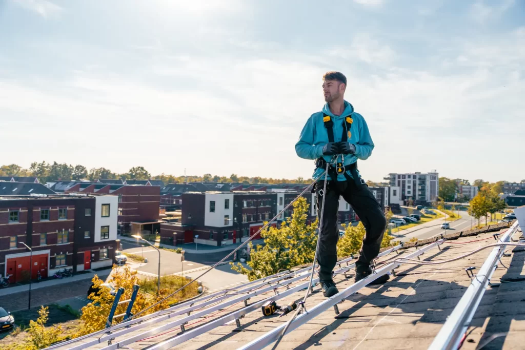 Monteur met valbeveiliging op een schuin dak tijdens de installatie