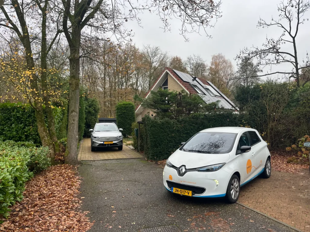 Woning met zonnepanelen en twee auto's op de oprit