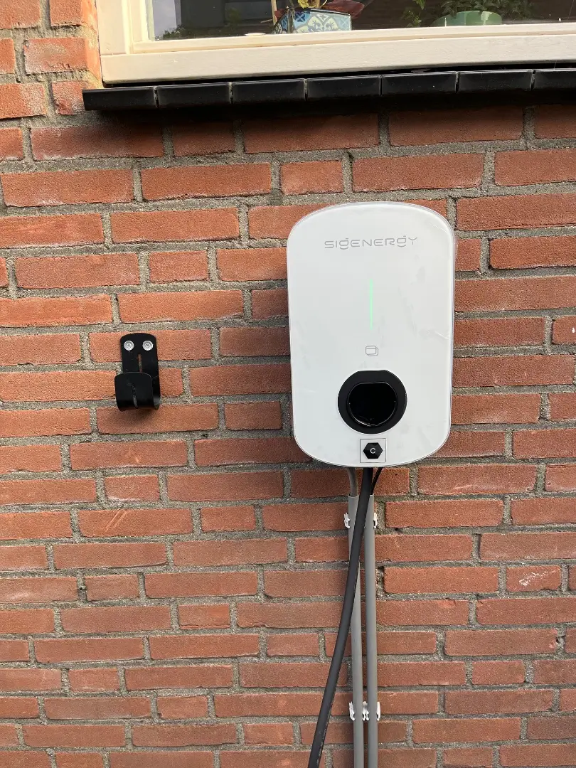 Laadpaal aan de bakstenen muur van een woning